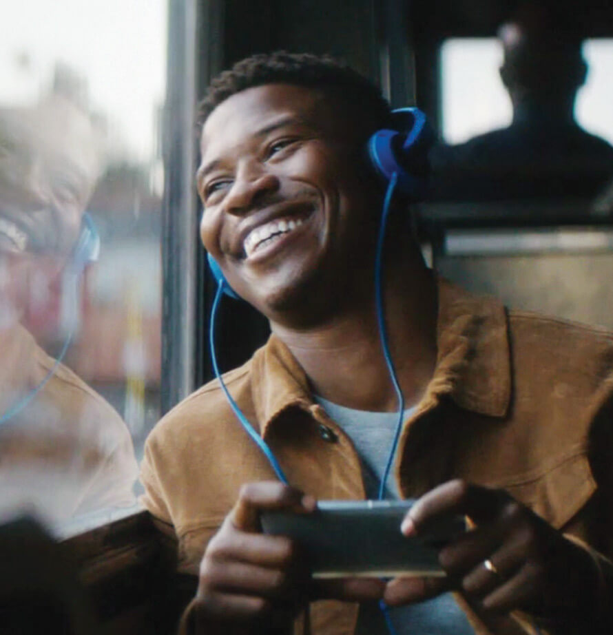 Man smiling and looking out a train window while listening to SiriusXM.