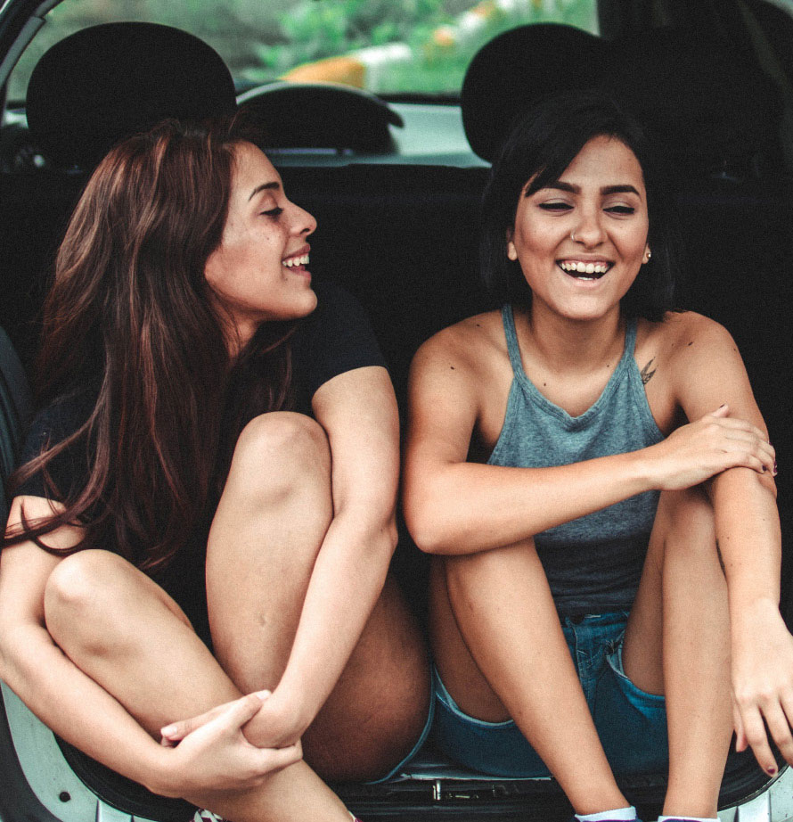 Two girls sitting in the back of their car listening to SiriusXM.