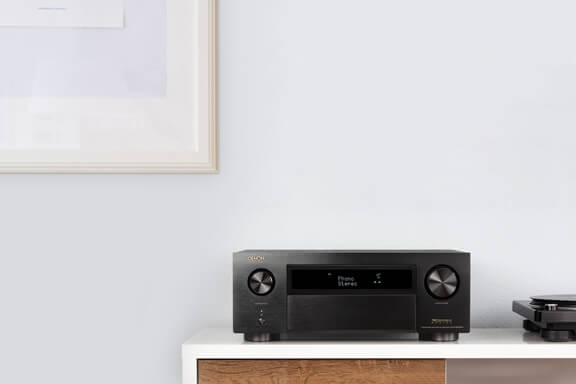 A Denon receiver on a shelf beside a record player.