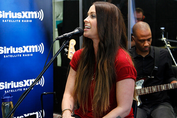 An image of Alanis Morissette singing in a SiriusXM studio.