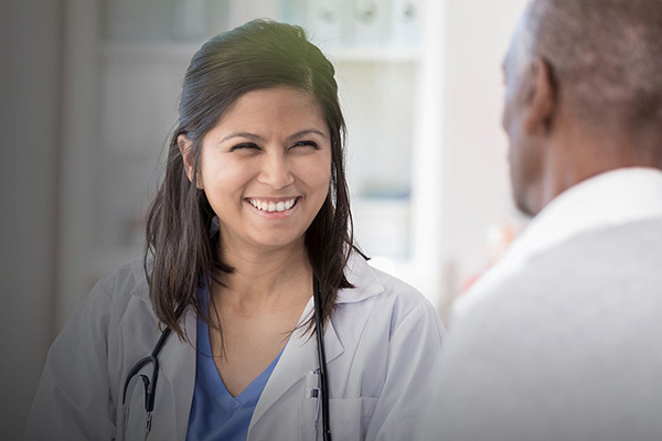 An image of a female-presenting doctor smiling at a colleague.