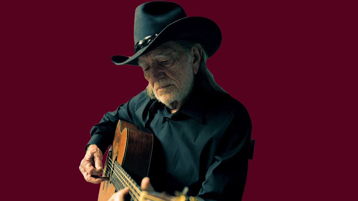 An image of Willie Nelson with his guitar.