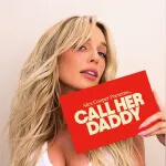Alex Cooper is pictured with long blonde hair holds a red sign that says Alex Cooper Presents CALL HER DADDY in bold white letters. She is posing in front of a plain light-coloured background—Listen to the Call Her Daddy podcast on SiriusXM.