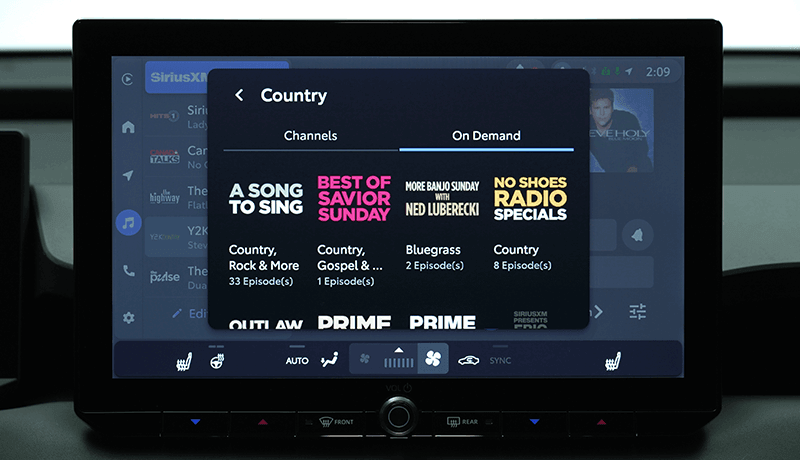 A SiriusXM infotainment screen for Toyota with 360L displays a selection of On Demand content available on SiriusXM, like A 'Song to Sing', 'Best of Savior Sunday', 'More Band Sunday', and 'No Shoes Radio Specials'.