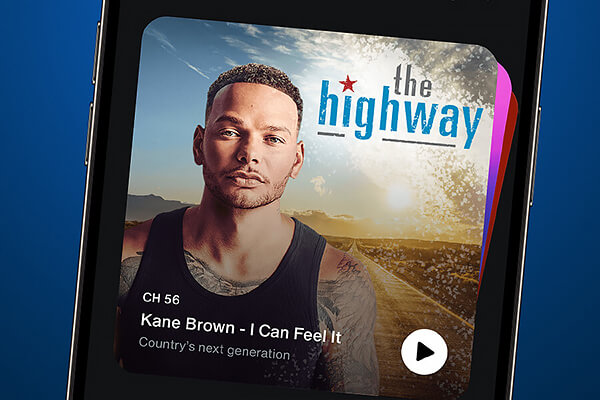 Sur l'écran d'un smartphone, l'application musicale affiche la chanson "I Can Feel It" de Kane Brown sur la chaîne The Highway, avec une image de Kane Brown et un paysage de campagne en arrière-plan.