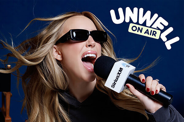 Une femme aux longs cheveux blonds porte des lunettes de soleil noires et tient un microphone SiriusXM, chantant ou parlant avec enthousiasme. Les mots UNWELL ON AIR apparaissent en caractères blancs gras sur fond bleu.