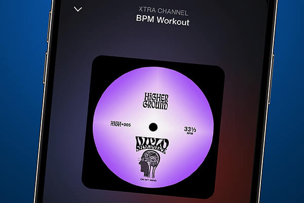 L'écran d'un smartphone affiche un morceau de musique intitulé BPM Workout de la chaîne XTRA. La pochette de l'album comporte une étiquette de vinyle violet avec le texte Higher Ground et un graphique stylisé représentant une tête.