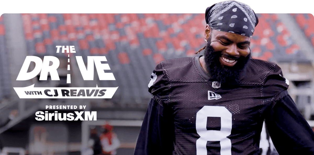 A smiling CJ Reavis is pictured in a black jersey with the number 8 and a bandana stands on a field. Text reads, The Drive with CJ Reavis, presented by SiriusXM.