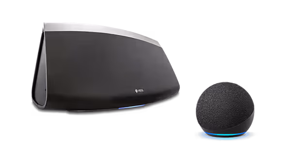 A large Denon black wireless speaker sits next to a smaller black Amazon smart speaker with a blue LED ring, perfect for enjoying SiriusXM via Amazon Alexa and the SiriusXM app.